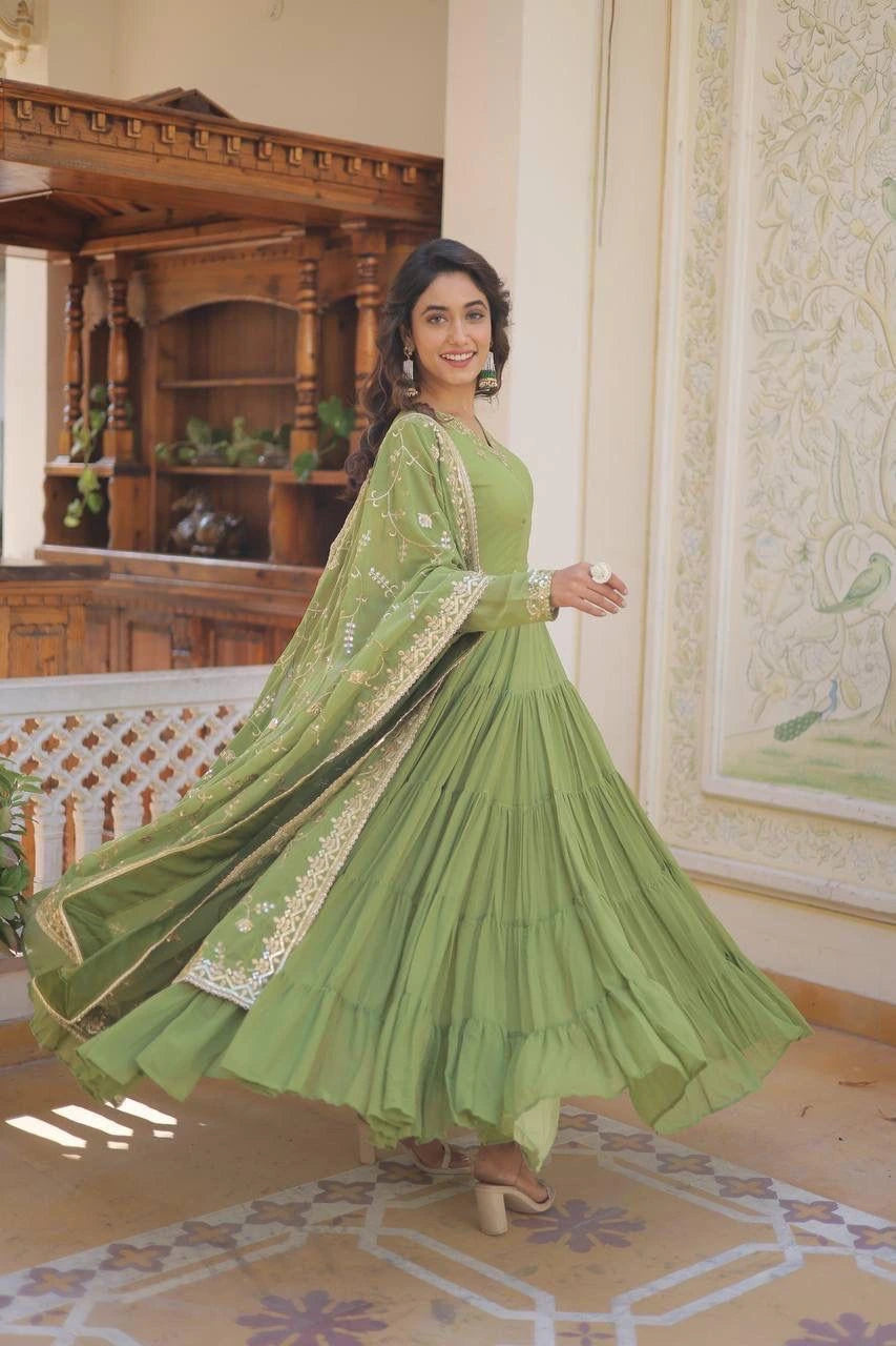 Woman in a green traditional outfit standing in an ornate room.